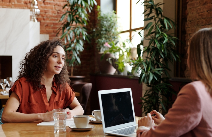 Women at desk with laptop talking to each other