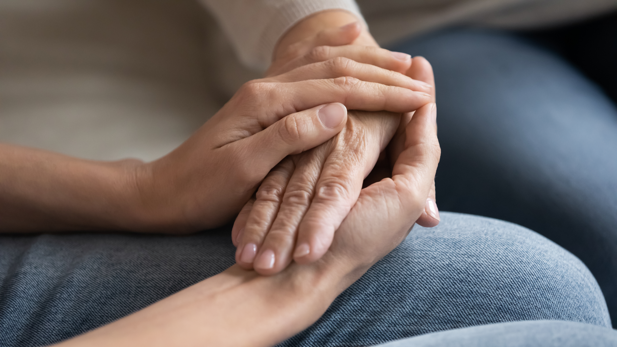 A caring woman supports an elderly person by holding their hand