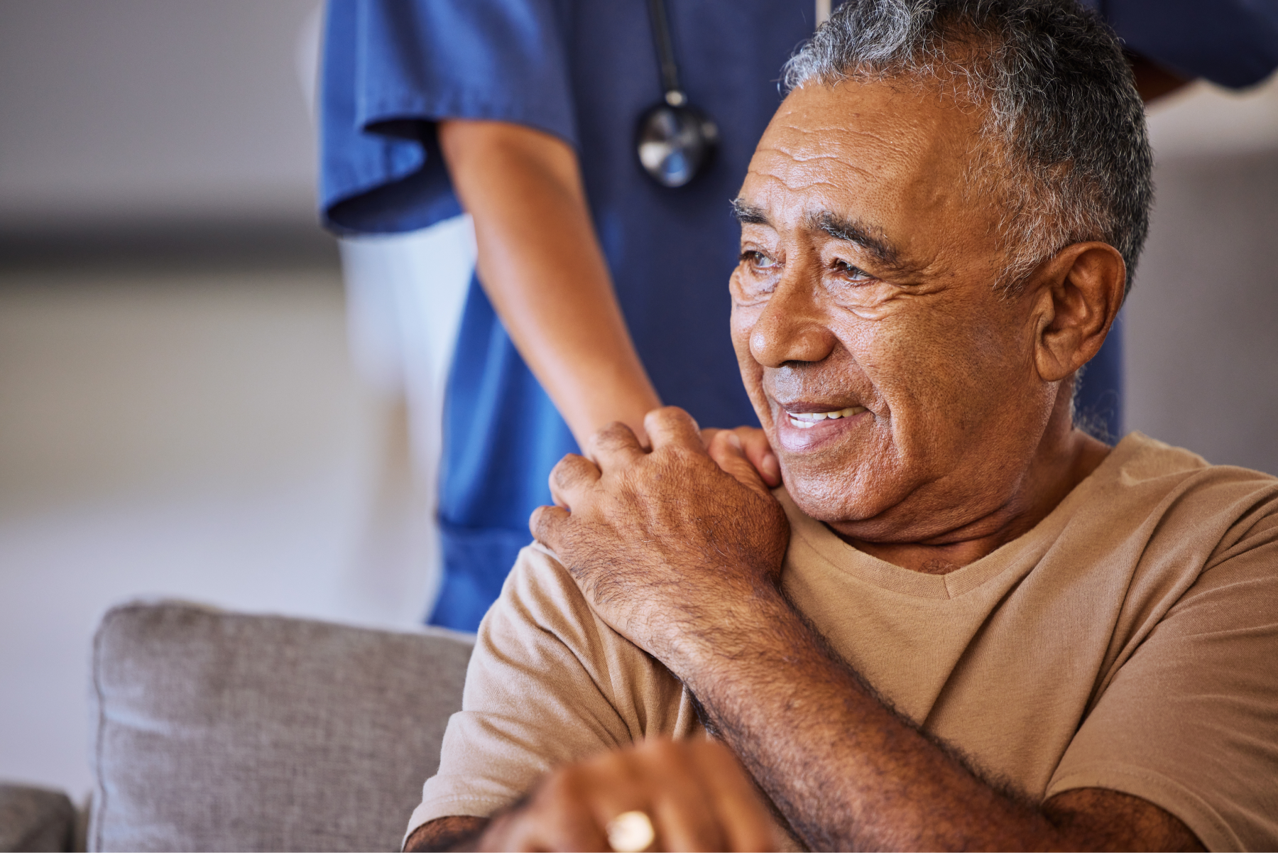 Caregiver holding hand of her sad senior patient and showing kindness while doing a checkup